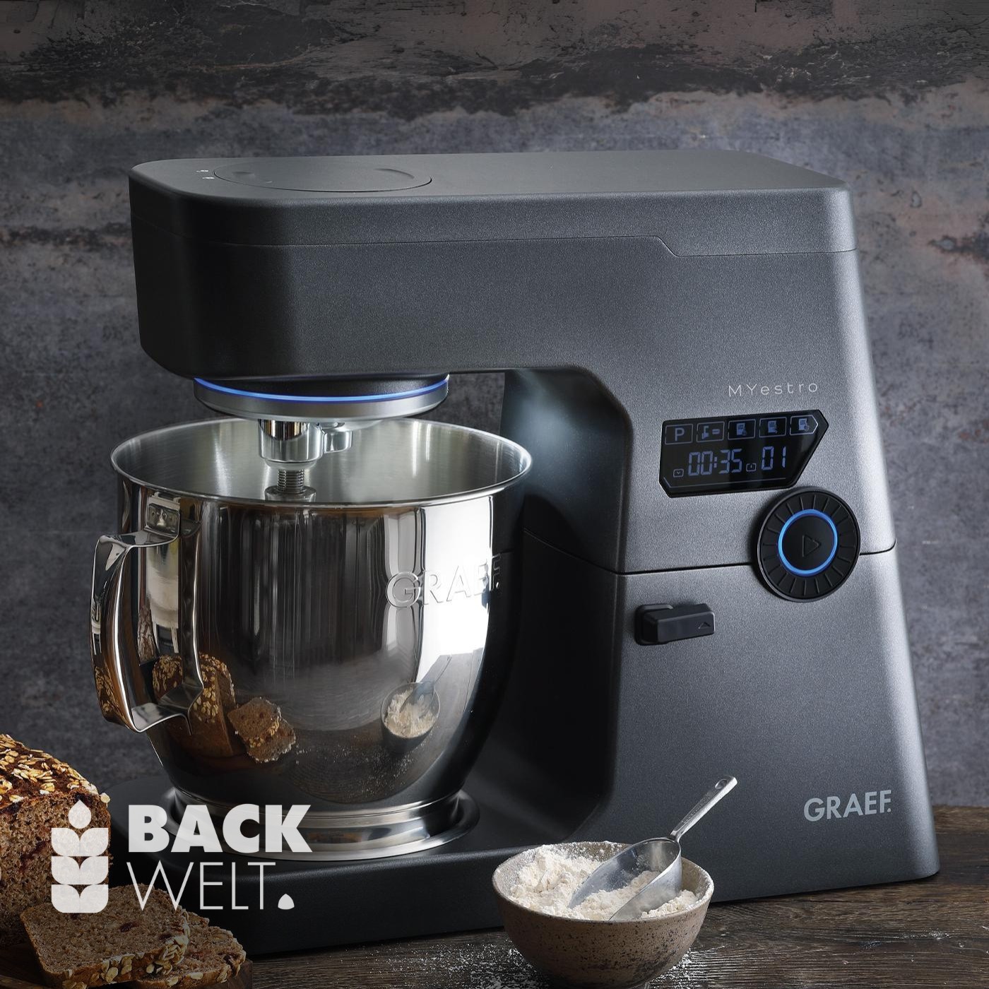 Küchenmaschine mit Schüssel, Mehl und Brot auf einem Holztisch