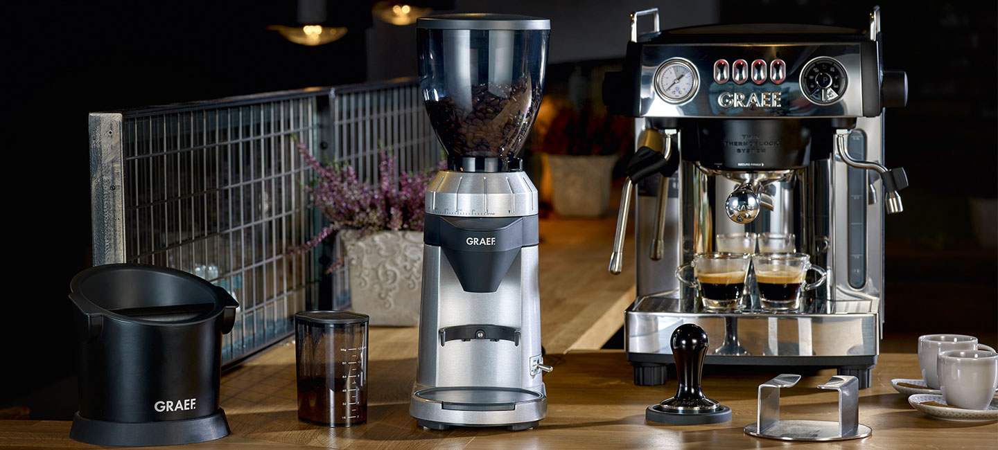 Kaffeemaschine, Kaffeemühle, Espressotassen, Tamper, Holzoberfläche, GRAEF-Marke.