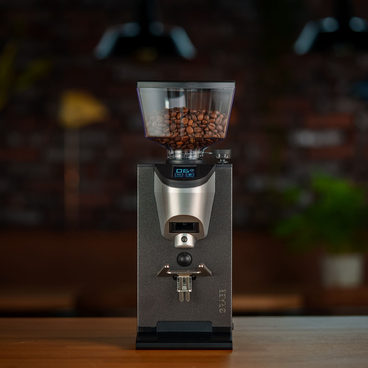 Kaffeemühle mit Bohnenbehälter auf einem Holztisch, digitaler Bildschirm