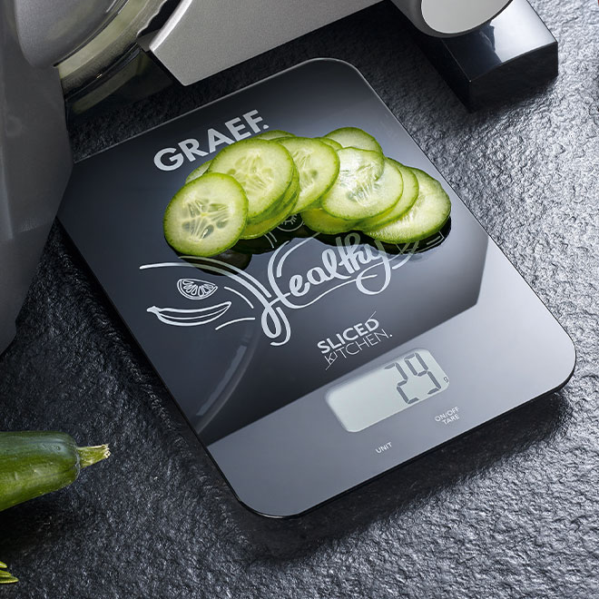 Waage mit Gurkenscheiben, zeigt 29g, 'Healthy Sliced Kitchen' Schriftzug.