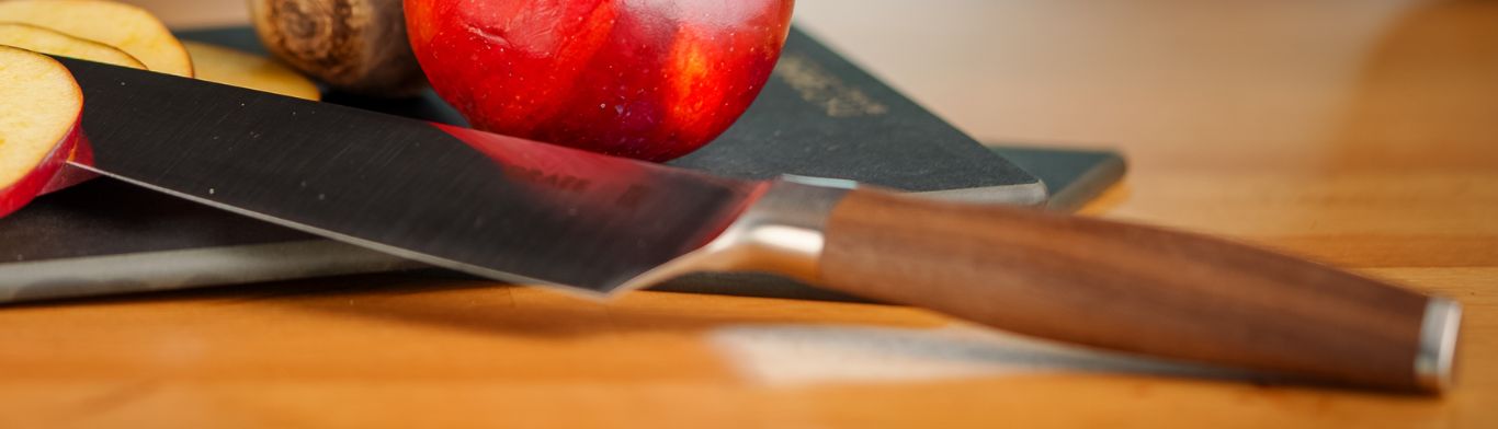 Apfel, Messer und Schneidebrett auf einem Holztisch. Nahaufnahme.