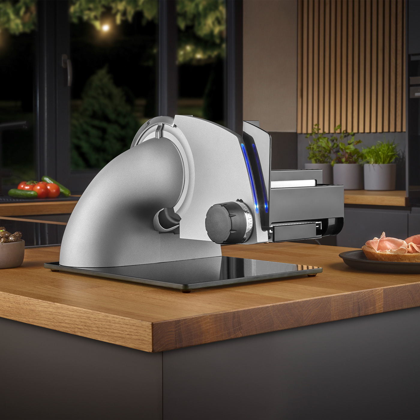 Elektrische Aufschnittmaschine auf Holztisch in Küche mit Essen