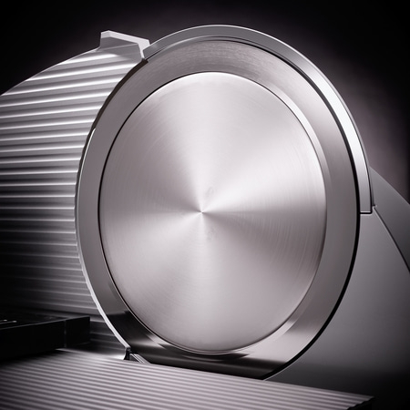 Nahaufnahme einer silbernen Aufschnittmaschine mit glänzender Oberfläche und Schatten