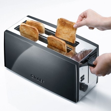 Grille-pain avec toasts. Personne retirant le pain grillé. Corps noir, éléments argentés.