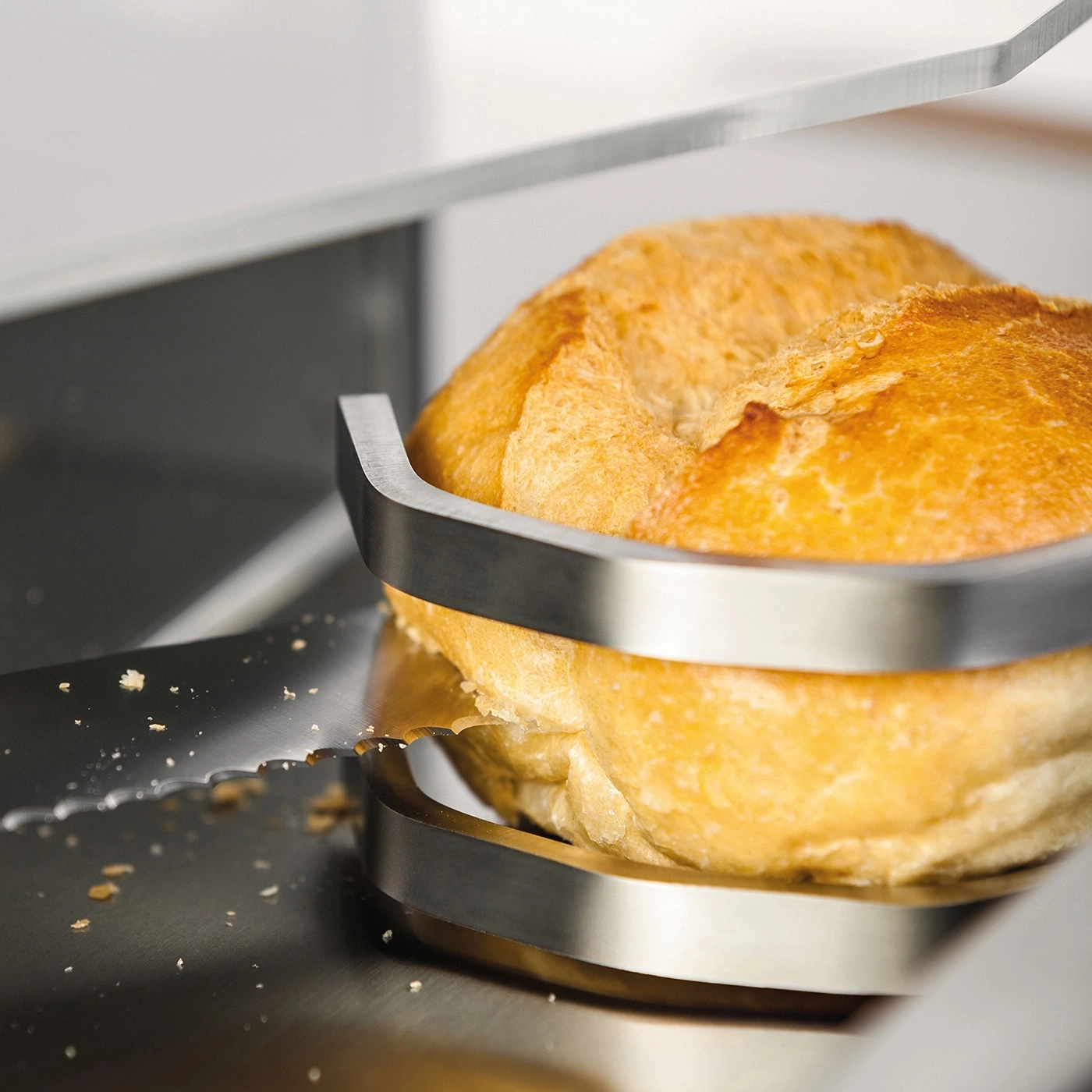 Brötchen wird mit einem Brotschneider geschnitten, Nahaufnahme, Detailaufnahme, Küche