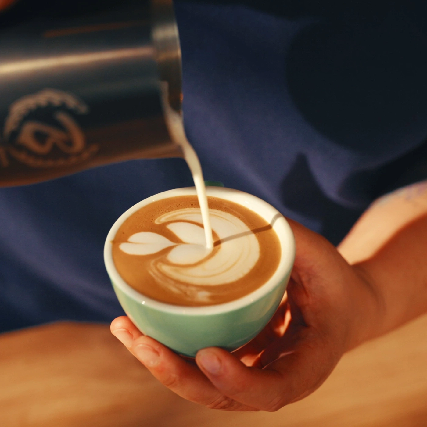 Barista gießt Latte Art in eine Tasse Kaffee.