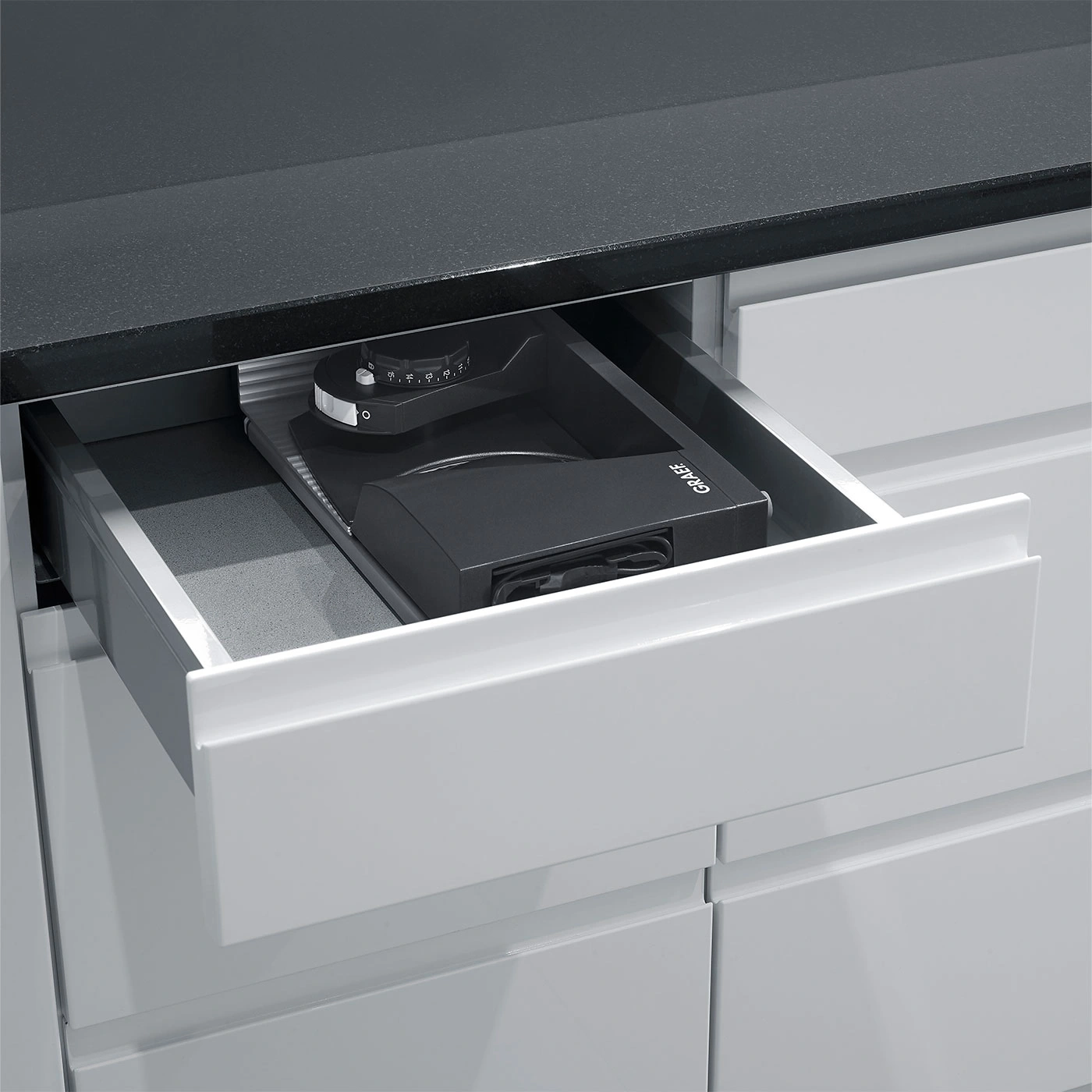 Schublade mit Kaffeemühle, schwarze Arbeitsplatte, Küchenschrank, Graef-Logo.