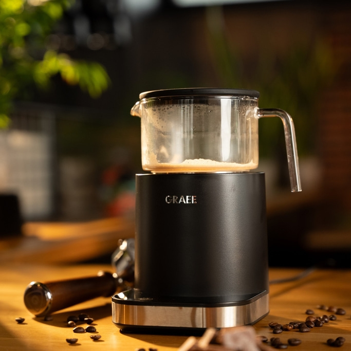 Kaffeemaschine mit Glasbehälter und Kaffeebohnen auf einem Holztisch