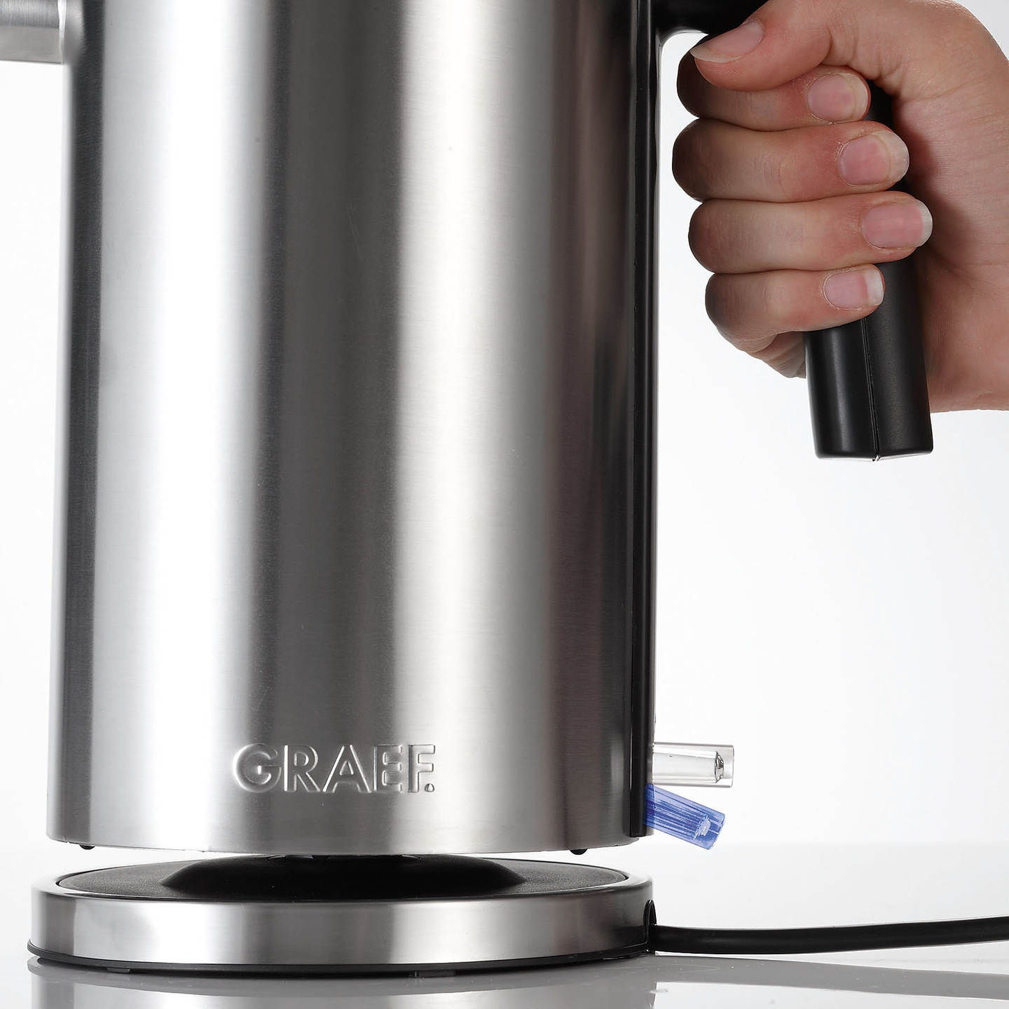 Edelstahl-Wasserkocher mit Griff und Hand, Nahaufnahme, Graef-Logo, Stromkabel