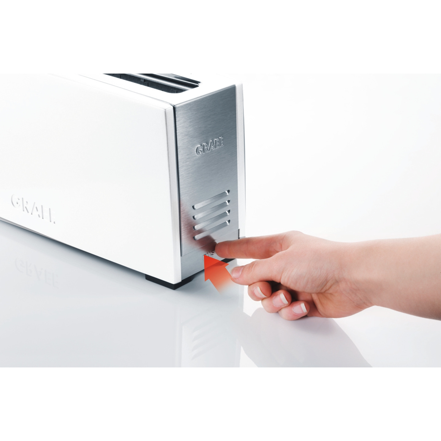 White toaster with silver accents, hand pressing button, red arrow indicating action.