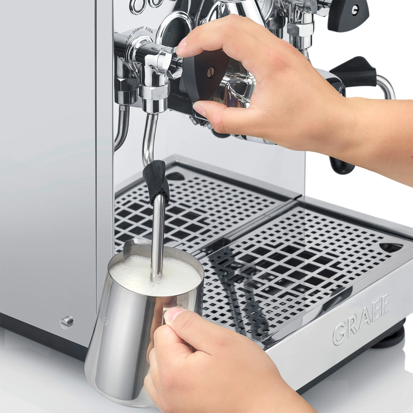 Person schäumt Milch mit einer Espressomaschine auf, um einen Latte zuzubereiten.