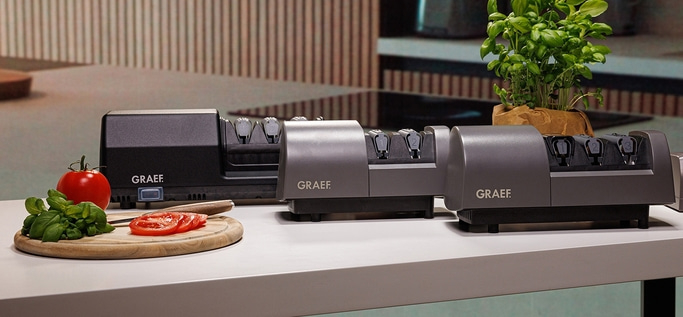 Drei elektrische Messerschärfer von Graef mit Tomaten und Basilikum.