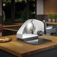 Ein Graef Allesschneider auf einem Holztresen mit einem belegten Brot daneben.