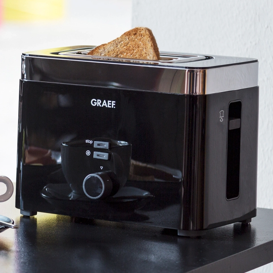 Schwarzer Toaster mit Toastbrot, Marke GRAEF, auf einer schwarzen Oberfläche.