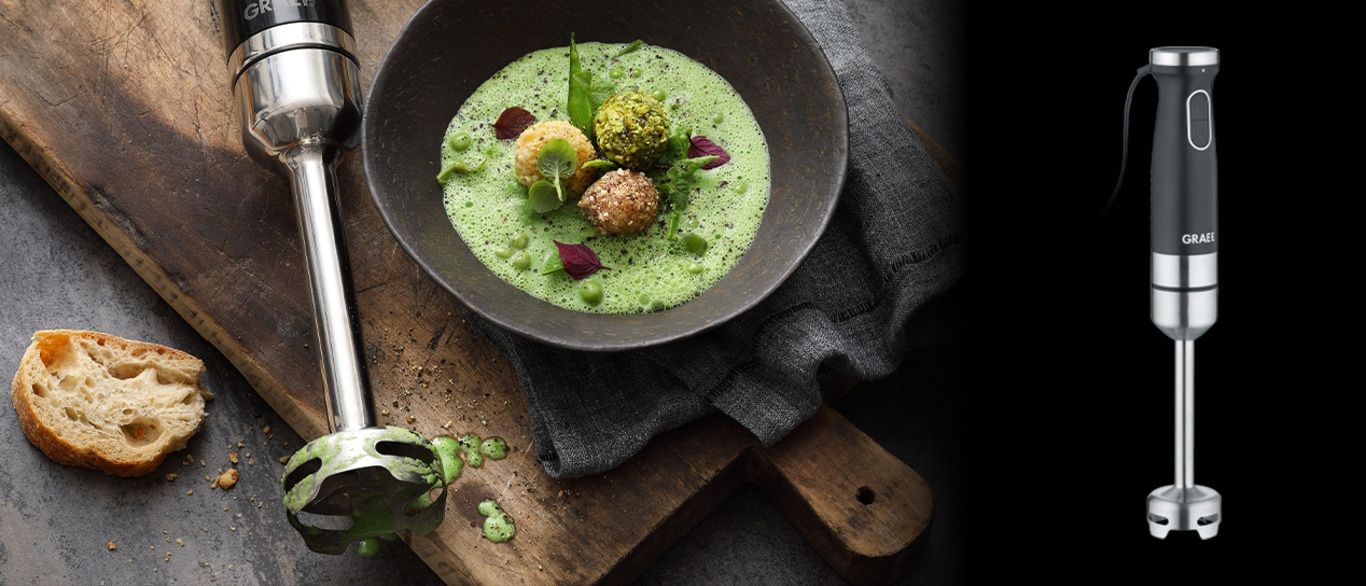 Handmixer und Suppe mit Brot auf Holzbrett