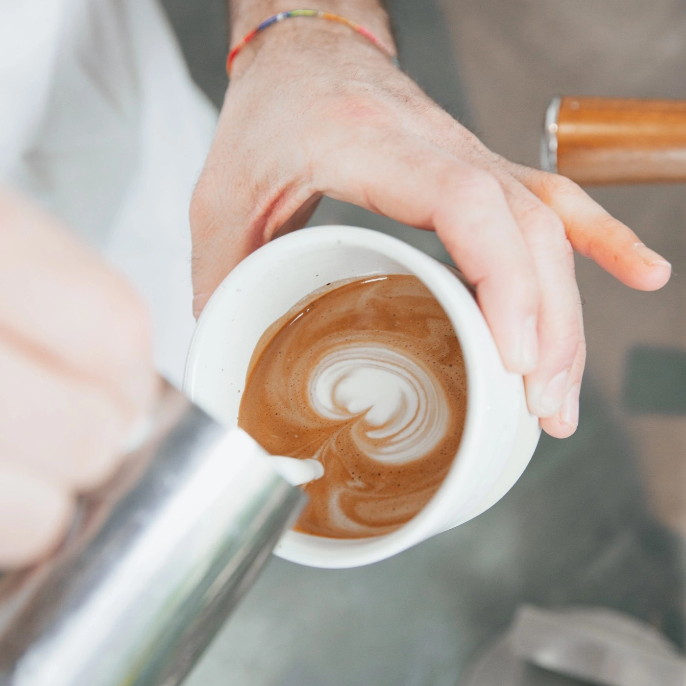 Kaffee-Kunst: Barista gießt Milch in eine Tasse, um ein Herz zu formen.