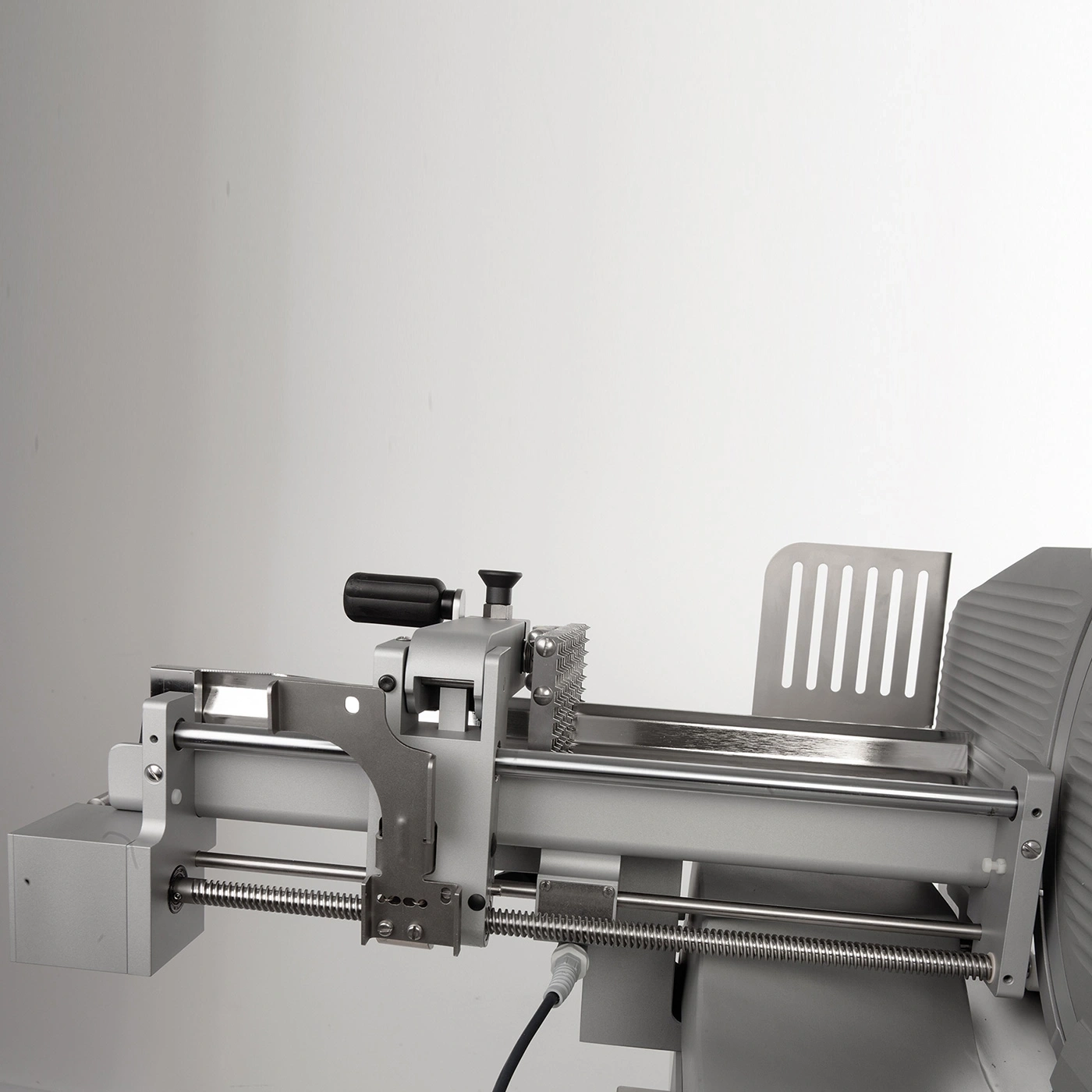 Nahaufnahme einer Fleischschneidemaschine mit Fokus auf den Schlitten und die Klinge.
