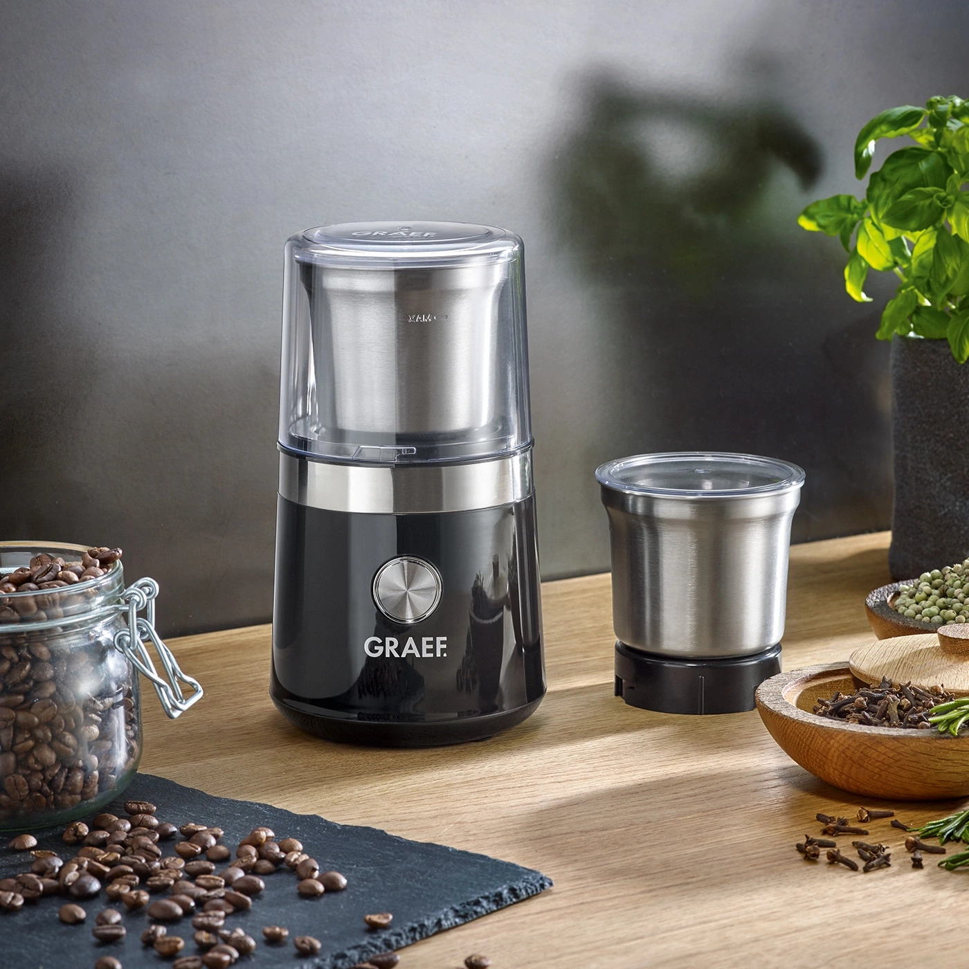 Kaffeemühle mit Zubehör und Zutaten auf Holzoberfläche, Nahaufnahme.