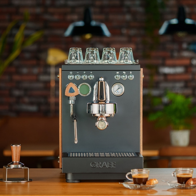 Espressomaschine mit Gläsern, Tassen und Zubehör auf einem Holztisch