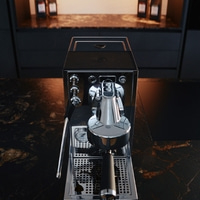 Eine glänzende Espressomaschine auf einer dunklen Marmorplatte in einer modernen Küche.