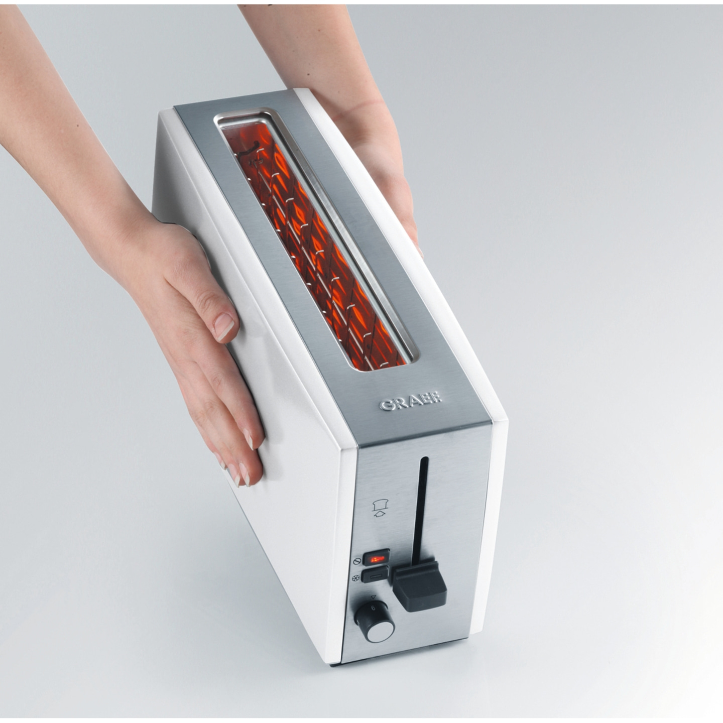 White toaster with silver accents held by hands, close-up shot, modern design