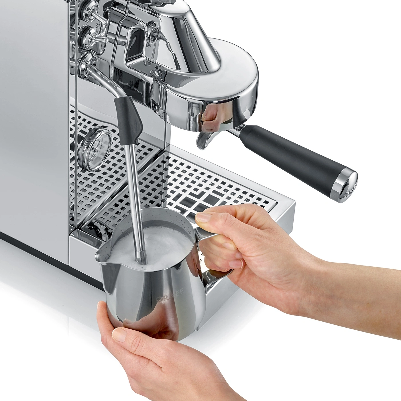 Eine Person schäumt Milch in einem Edelstahlkrug mit einer Espressomaschine.