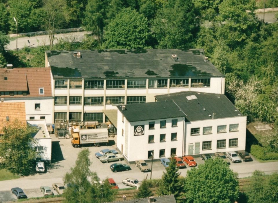 Luftaufnahme von Gebäuden mit Bäumen und geparkten Autos in der Nähe.