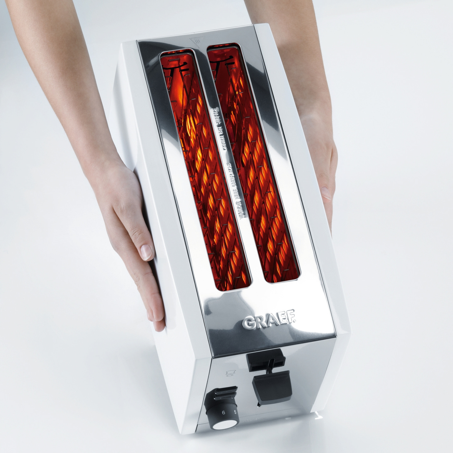 Grille-pain avec éléments chauffants incandescents, tenu par des mains, sur fond blanc.