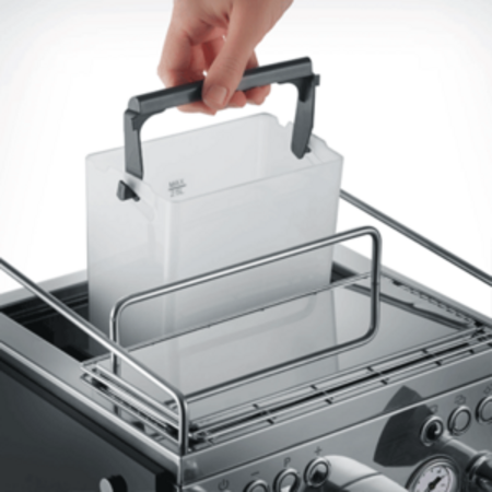 Hand removing water tank from espresso machine for refilling, close-up shot.