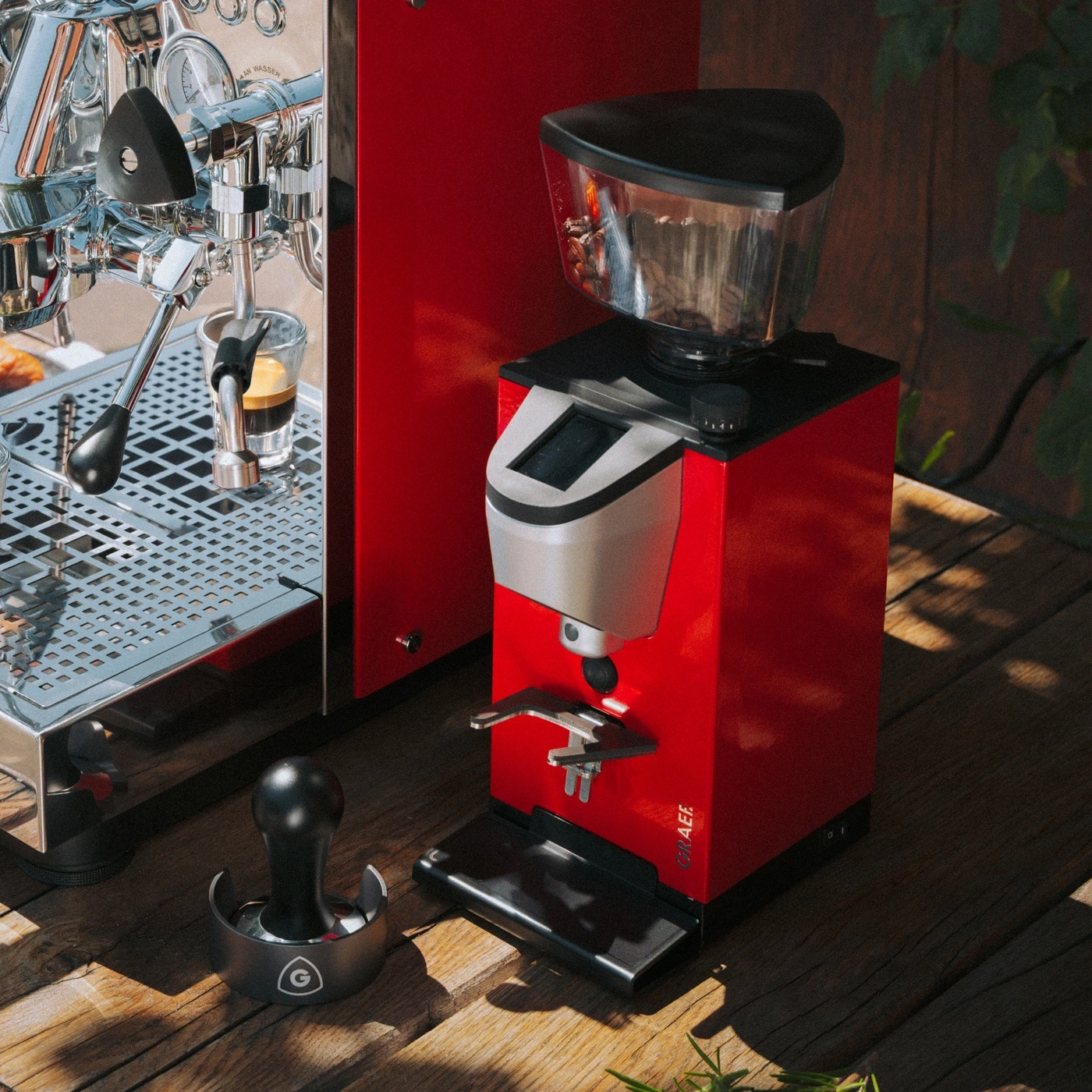 Eine rote Espressomaschine und ein Kaffeemühlen-Set stehen auf einer Holzoberfläche.