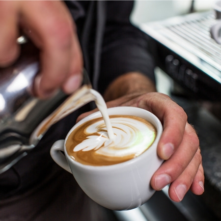 Kaffee Latte Art, Hände halten Tasse, Milch gießen, Barista-Kunst, Kaffeekunst