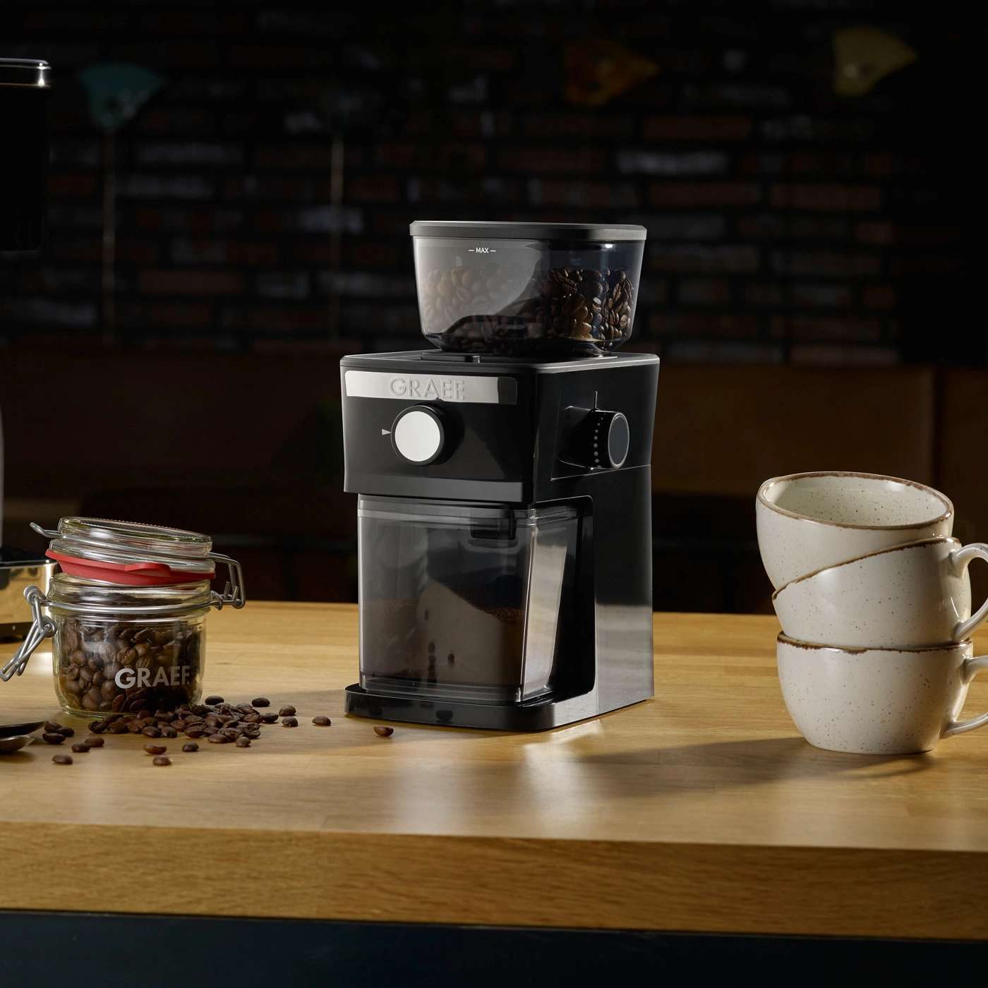 Kaffeemühle mit Bohnen, Tassen und Kaffeebohnen auf Holzoberfläche