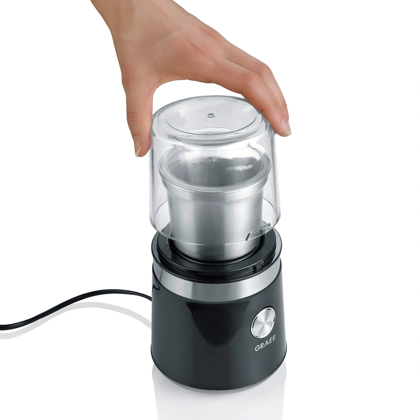 Hand öffnet Kaffeemühle mit transparentem Deckel und schwarzem Gehäuse.