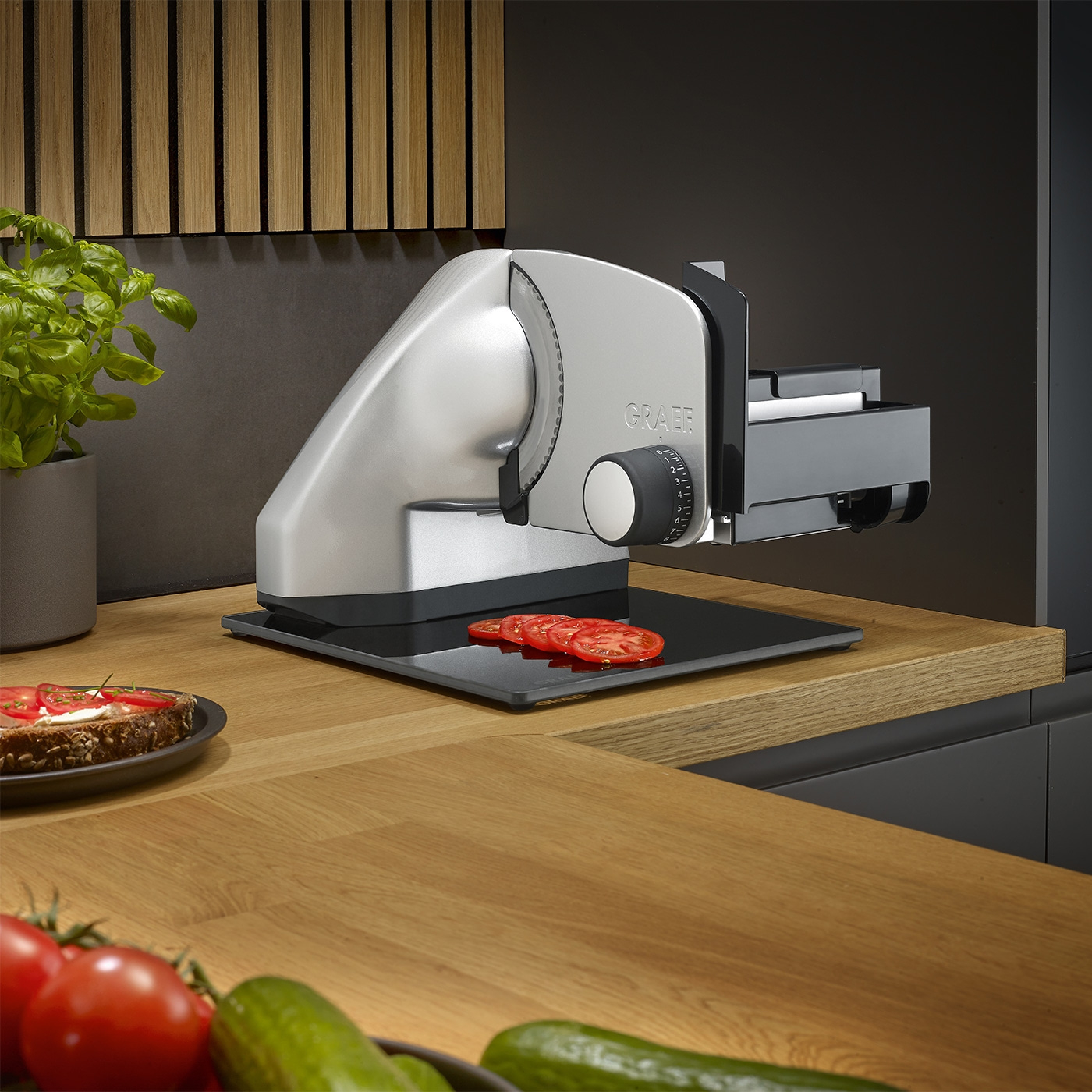 Graef Allesschneider mit Tomaten auf Holzoberfläche und Gemüse im Vordergrund