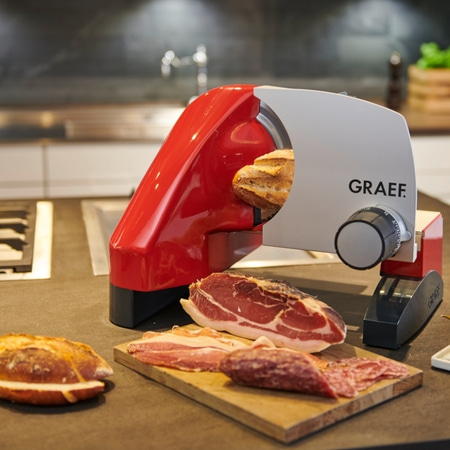 Ein elektrischer Brötchenschneider in Aktion mit Schinken und Brot