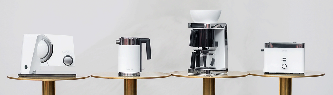 White kitchen appliance set on golden tables against a light background.