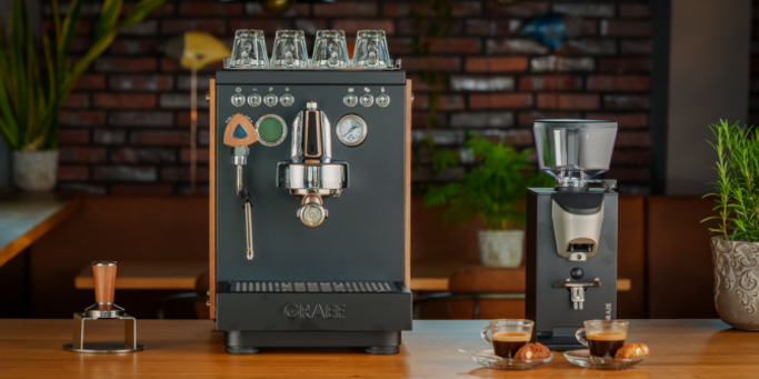 Espressomaschine und Kaffeemühle mit zwei Tassen Espresso auf einem Holztisch.