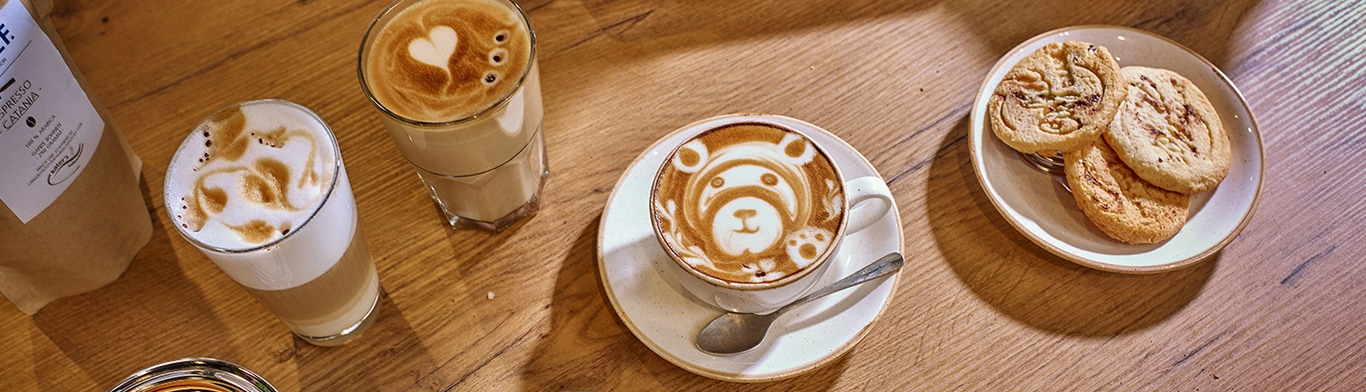 Art de café, biscuits sur une assiette, surface en bois, ambiance chaleureuse, latte art.