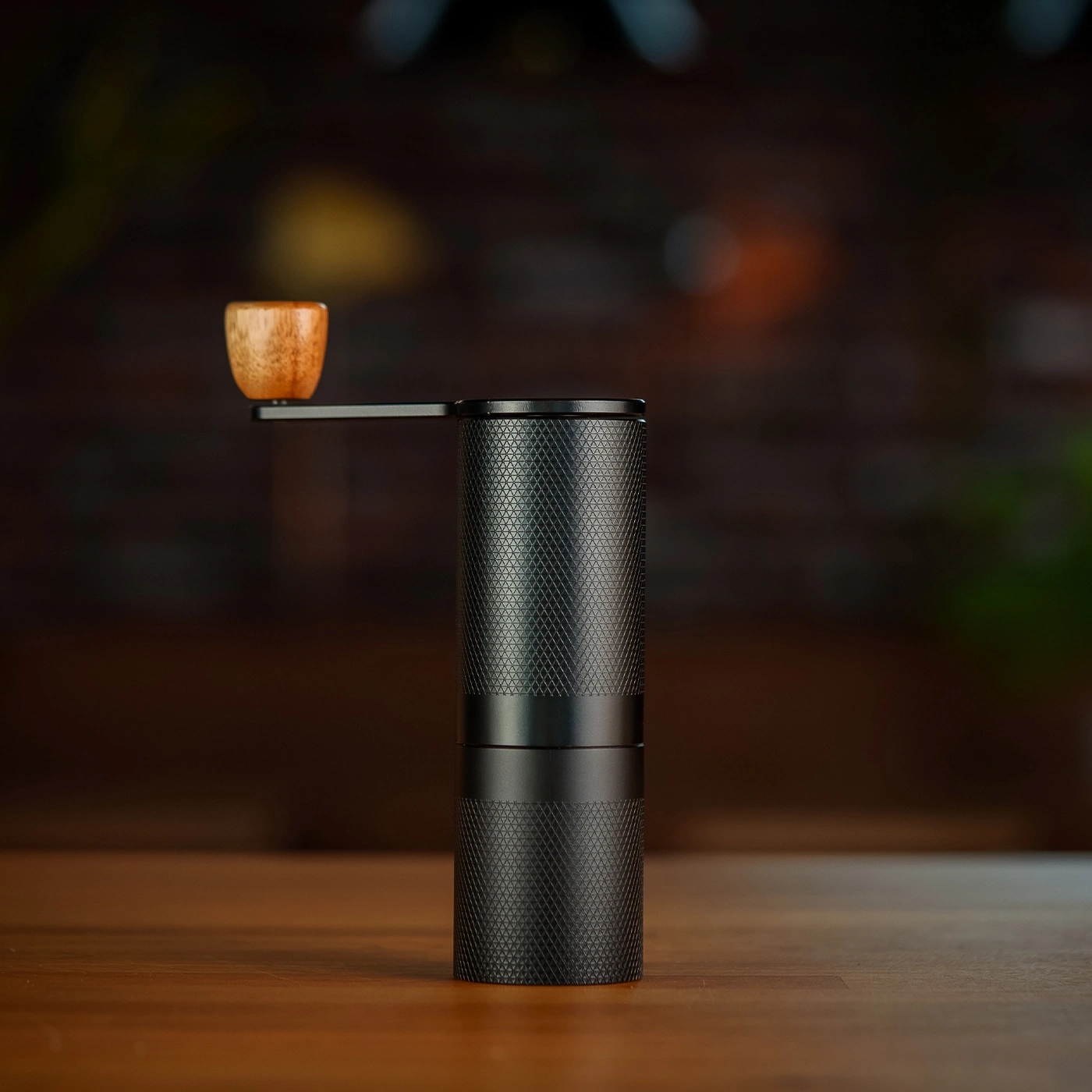Schwarze Kaffeemühle mit Holzgriff auf Holzoberfläche, Nahaufnahme.