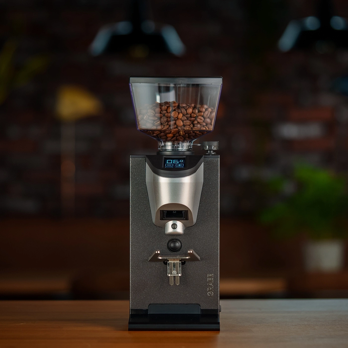Kaffeemühle mit Bohnenbehälter auf einem Holztisch, digitaler Bildschirm