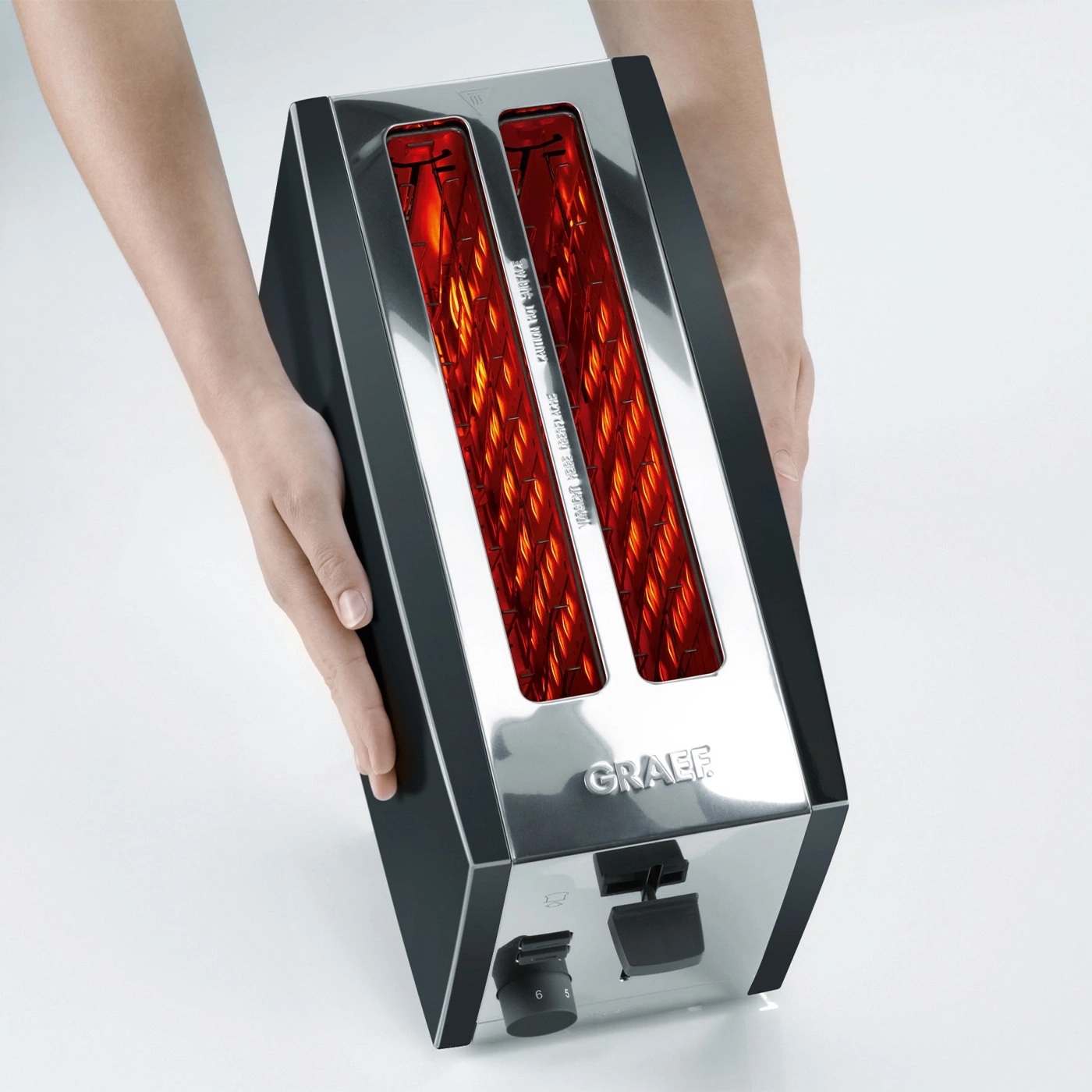 Hände halten einen Toaster mit leuchtenden Heizdrähten und der Marke GRAEF.