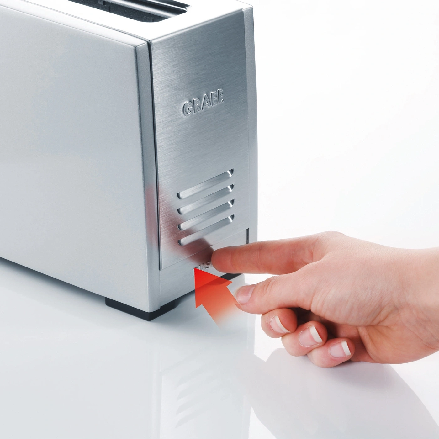 Silberner Toaster mit Hand, die einen Knopf drückt, roter Pfeil zeigt