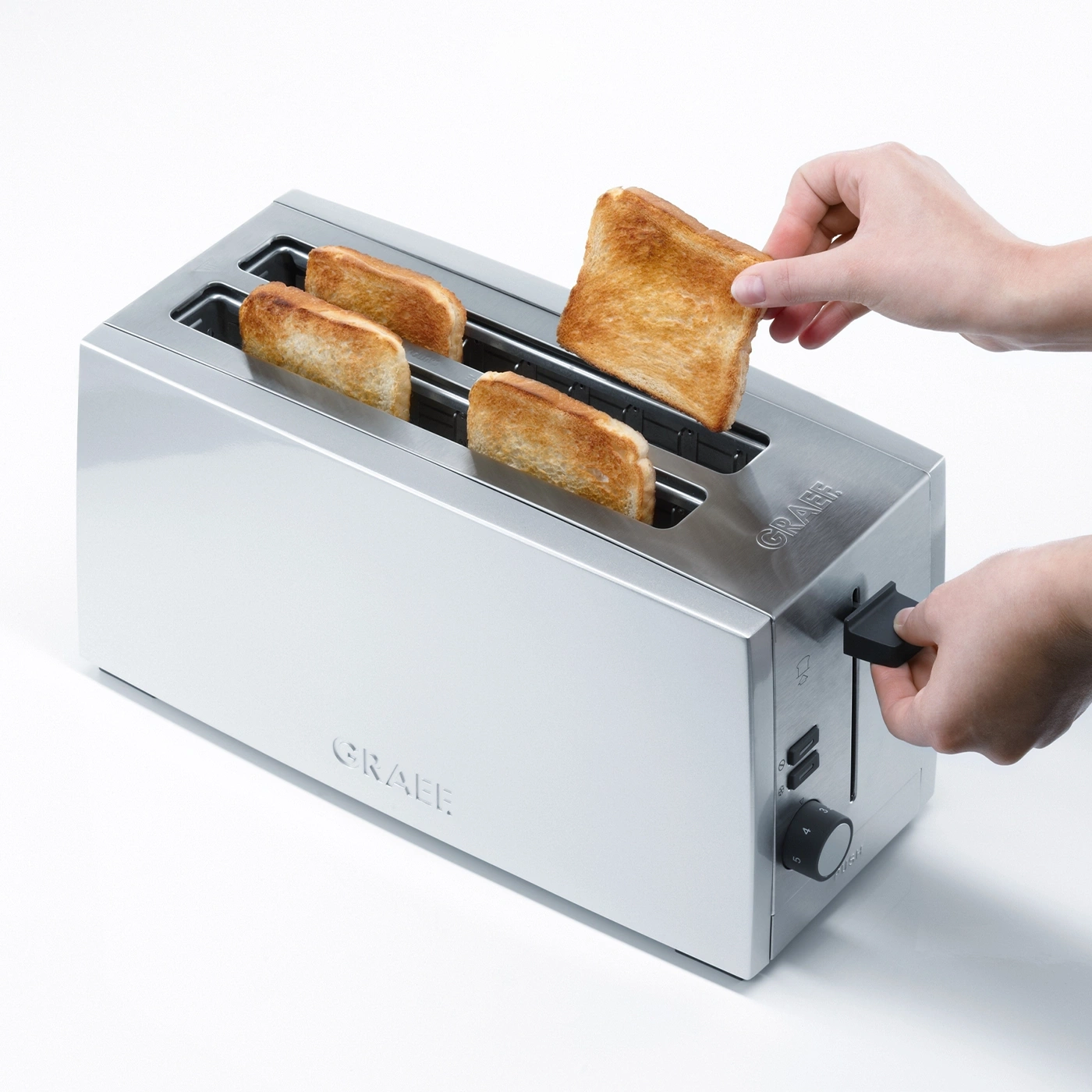 Ein Toaster mit Toast, eine Hand nimmt Toast heraus, silbernes Gerät, GRAEF.