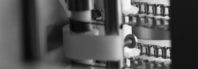 Gros plan d'une chaîne métallique et d'une pièce de machine en noir et blanc.