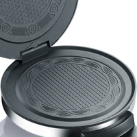 Offener Waffelmaker mit detaillierten Backflächen und silbernem Rand.
