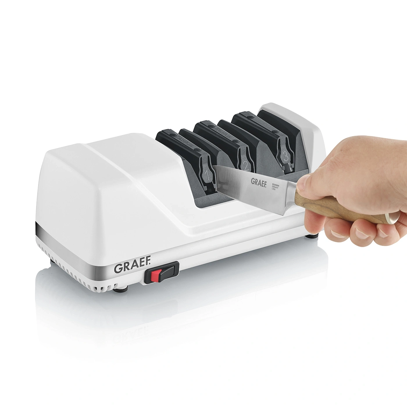 Ein elektrischer Messerschärfer von Graef mit einem Messer, das von einer Hand eingeführt wird.