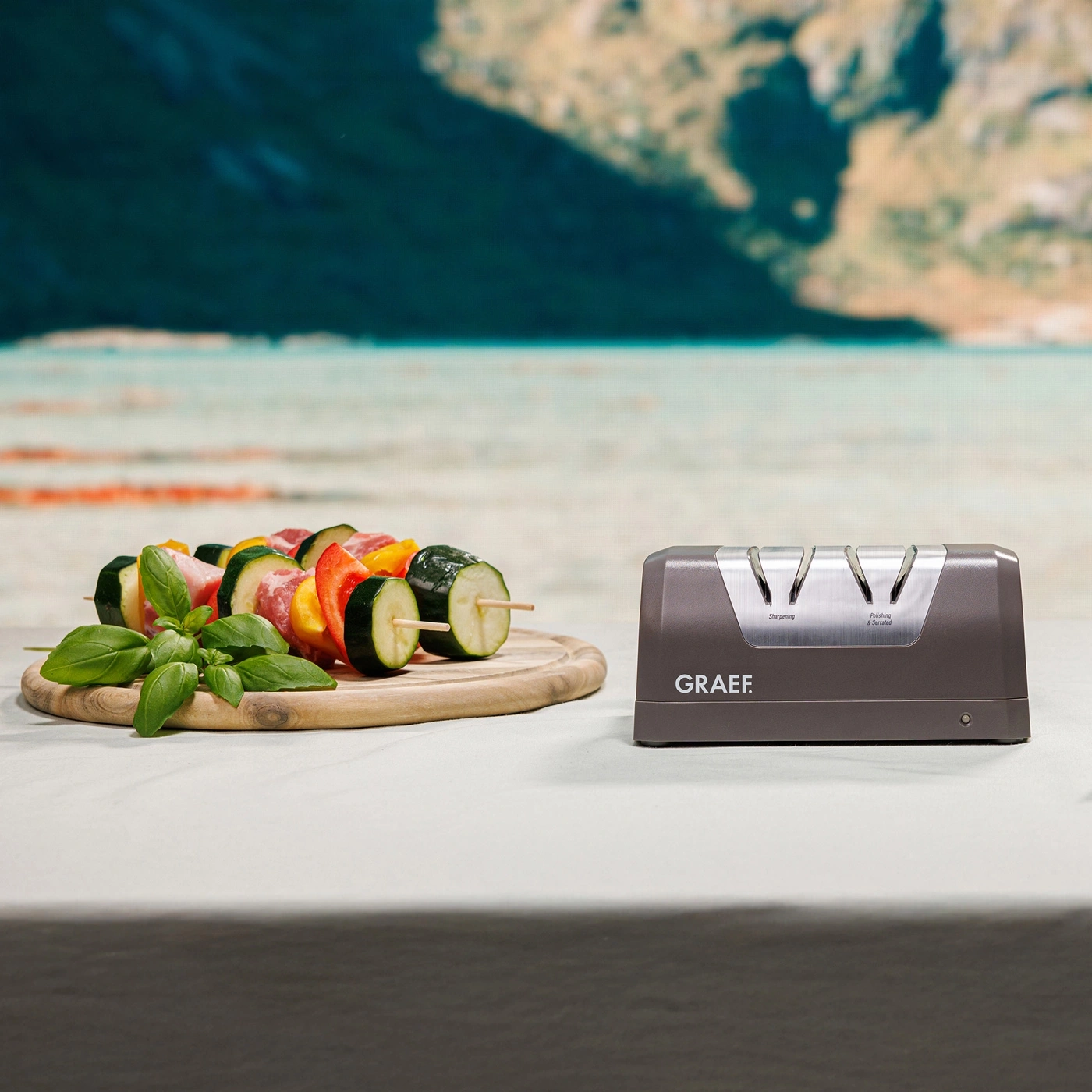 Gemüse-Spieße und Messerschärfer auf Tisch mit Berglandschaft im Hintergrund