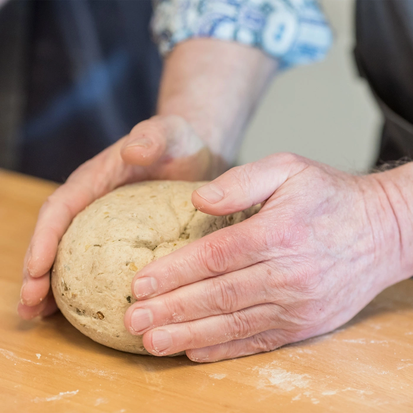 Hände kneten Teig auf Holzoberfläche. Nahaufnahme von Brotbacken.