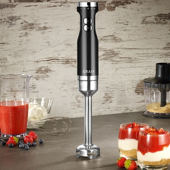 Schwarzer Stabmixer mit Früchten und Desserts auf einem Tisch