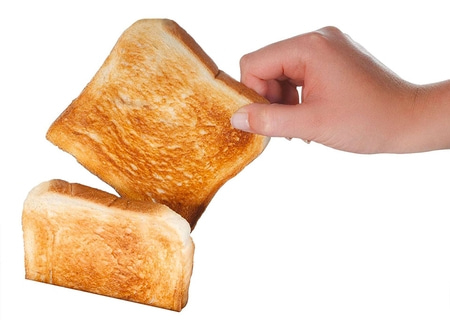 Toasted bread held by a hand against a white background, close up.